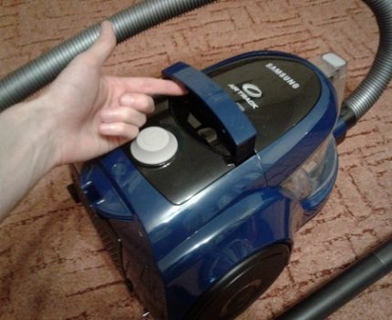The handle is pulled up to carry the vacuum cleaner Two-in-one button handle