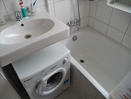 Shallow sink in a small bathroom White hinged sink over the washing machine